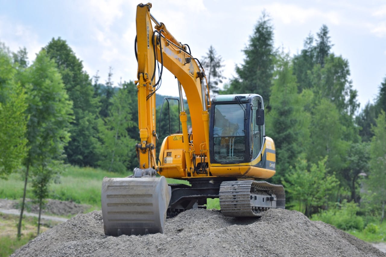 our-services-2 A yellow excavator on a pile of gravel in a lush, green forest setting in Poland.